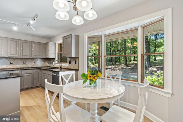 kitchen with plenty of natural light, gray cabinets, an inviting chandelier, and a sink