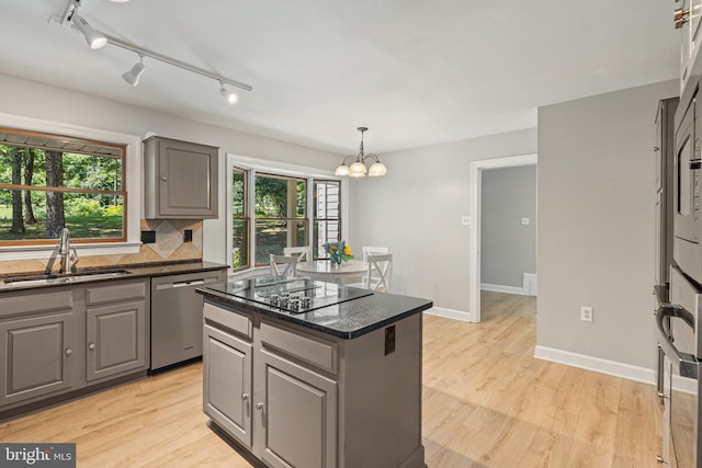 kitchen featuring stainless steel dishwasher, gray cabinetry, light wood-type flooring, and a sink