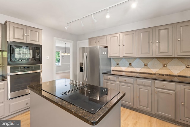 kitchen featuring black appliances, tasteful backsplash, light wood-type flooring, and gray cabinetry