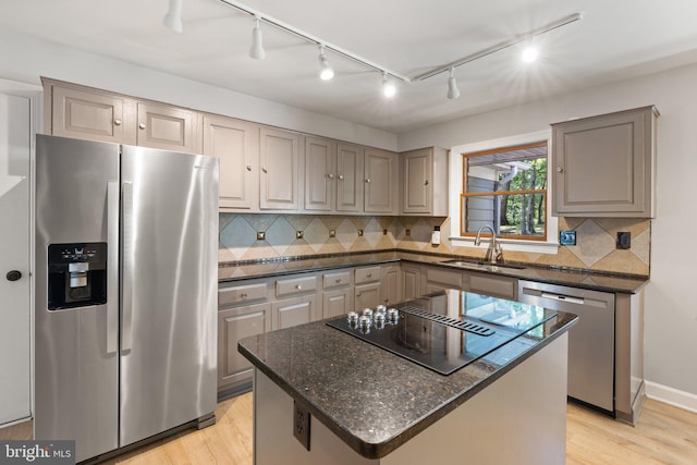 kitchen featuring a kitchen island, gray cabinets, light wood-style floors, stainless steel appliances, and a sink