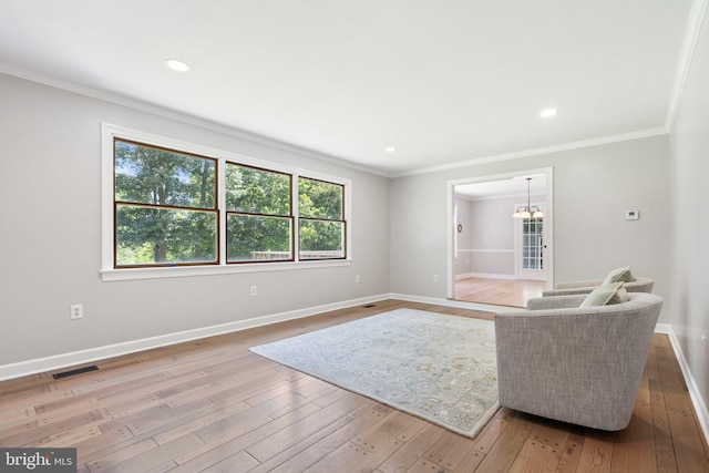 sitting room with hardwood / wood-style floors, an inviting chandelier, crown molding, and baseboards