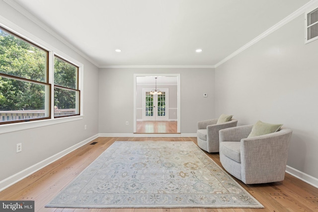 living area featuring light wood finished floors, baseboards, crown molding, and an inviting chandelier