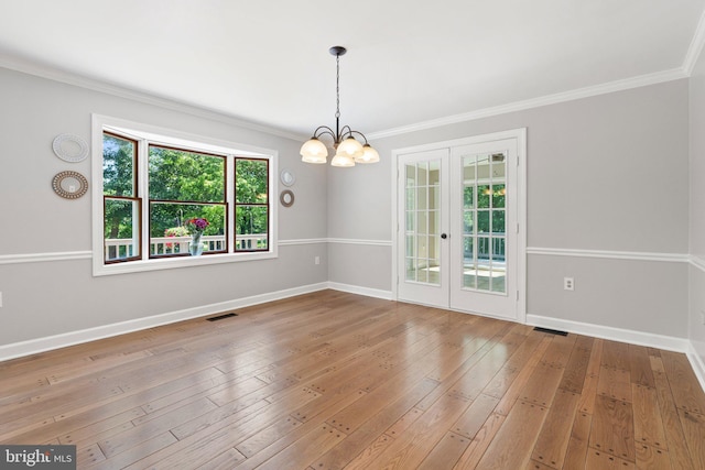 unfurnished room with hardwood / wood-style floors, crown molding, a notable chandelier, and baseboards