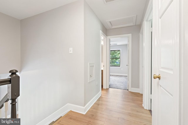 corridor featuring visible vents, baseboards, attic access, an upstairs landing, and light wood-style flooring