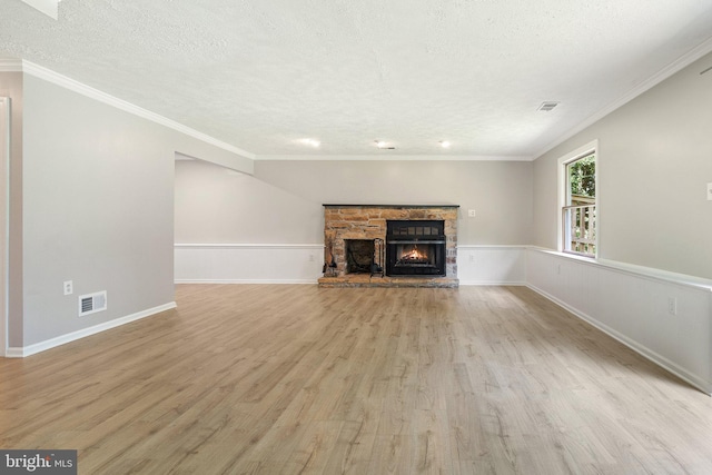 unfurnished living room with visible vents, a fireplace, a textured ceiling, and wood finished floors