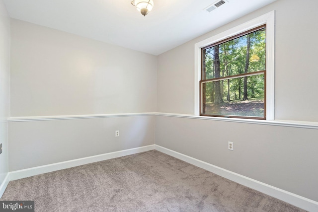 empty room with carpet, visible vents, and baseboards