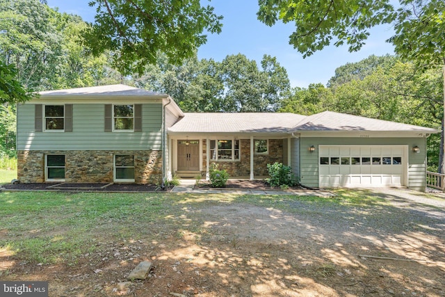 split level home featuring stone siding, driveway, a front lawn, and a garage