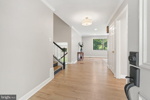 corridor featuring light wood finished floors, stairs, and crown molding