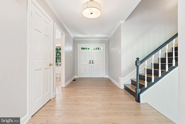 entrance foyer with crown molding, light wood-style flooring, stairway, and baseboards