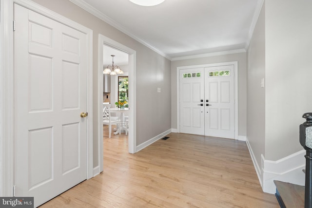 foyer entrance featuring a notable chandelier, crown molding, light wood-type flooring, and baseboards