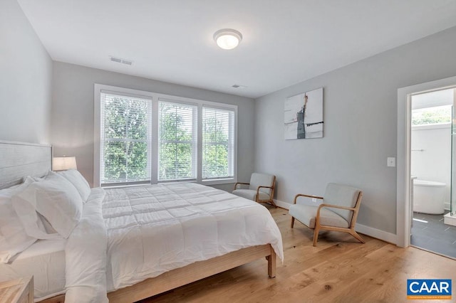 bedroom with visible vents, light wood-style flooring, ensuite bathroom, and baseboards