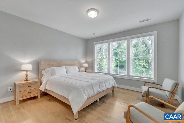 bedroom with light wood-type flooring, visible vents, and baseboards