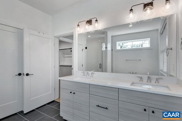 full bathroom featuring tile patterned flooring, a stall shower, double vanity, and a sink