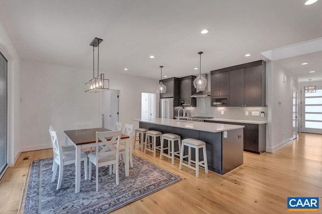 dining area with a chandelier, recessed lighting, light wood-style flooring, and baseboards