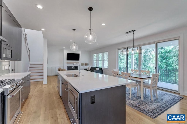 kitchen with light wood finished floors, a sink, recessed lighting, appliances with stainless steel finishes, and light countertops