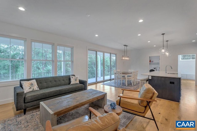 living area with washer / dryer, light wood-style flooring, recessed lighting, and baseboards