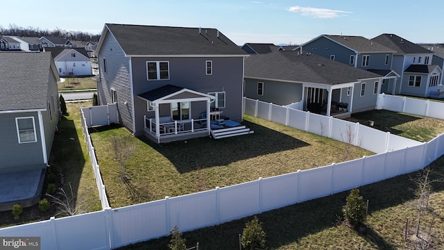 back of property with a fenced backyard, a wooden deck, a lawn, and a residential view
