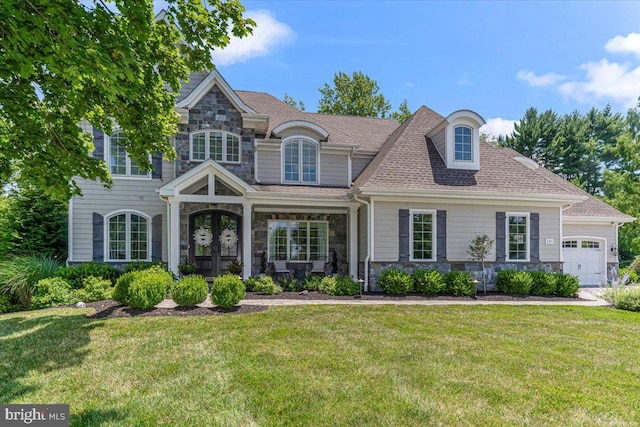 view of front of home featuring stone siding, french doors, an attached garage, and a front lawn