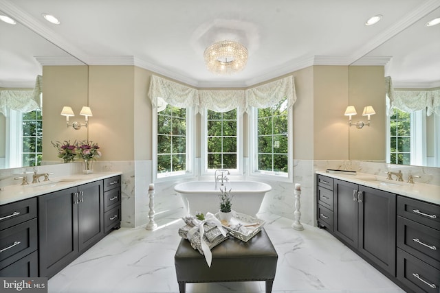 full bath featuring marble finish floor, a freestanding tub, a healthy amount of sunlight, and a sink