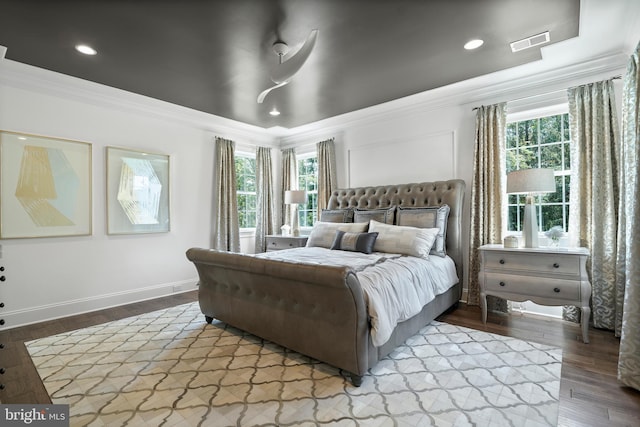 bedroom featuring visible vents, multiple windows, wood finished floors, and crown molding