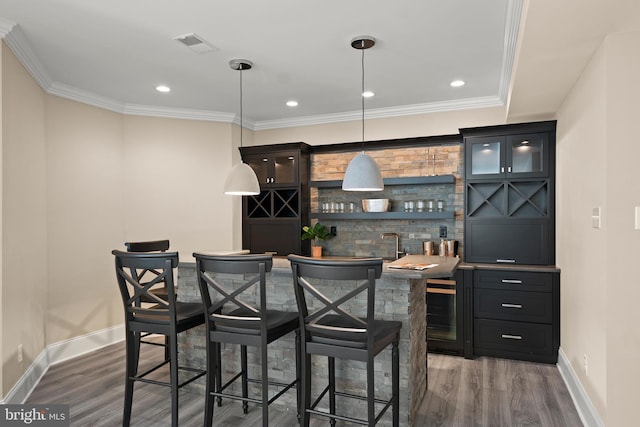 bar featuring visible vents, crown molding, baseboards, wet bar, and wood finished floors