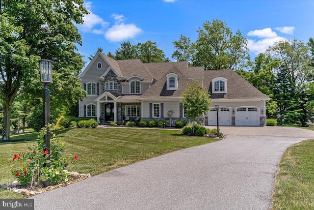 view of front of property with a front lawn, an attached garage, stone siding, and driveway