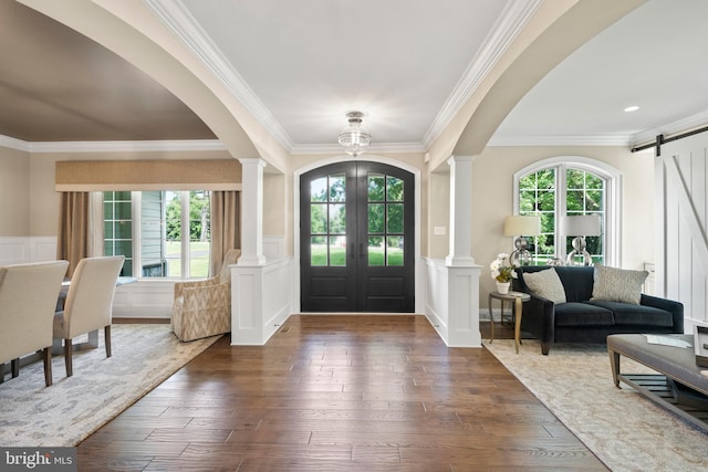 entryway featuring a barn door, wood finished floors, arched walkways, and ornate columns