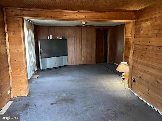 unfurnished living room with wooden walls, wood ceiling, and ceiling fan