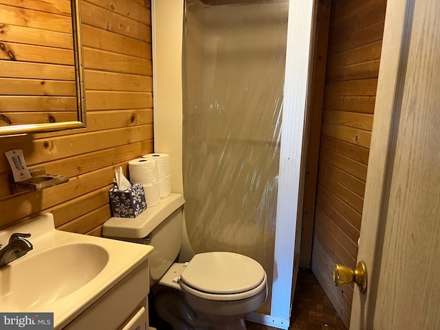 bathroom featuring vanity, toilet, and wood walls