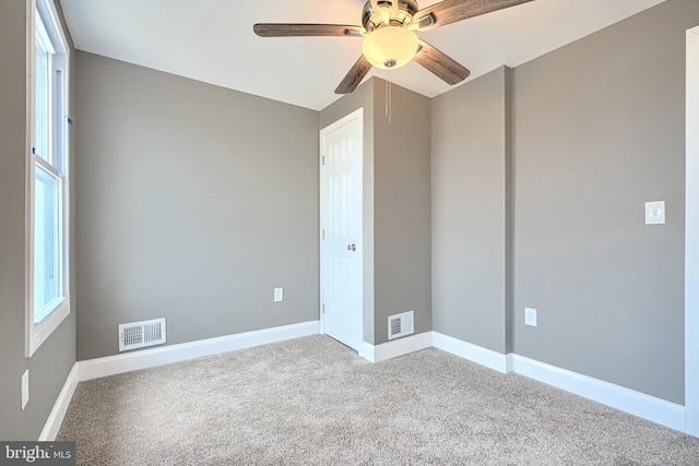 carpeted spare room featuring visible vents, baseboards, and a ceiling fan