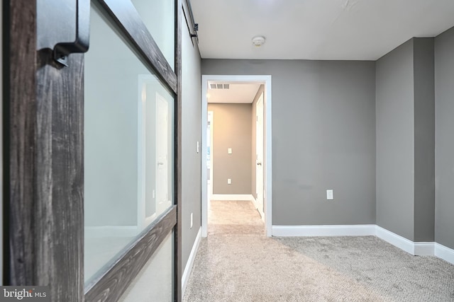 hall with visible vents, baseboards, and carpet floors