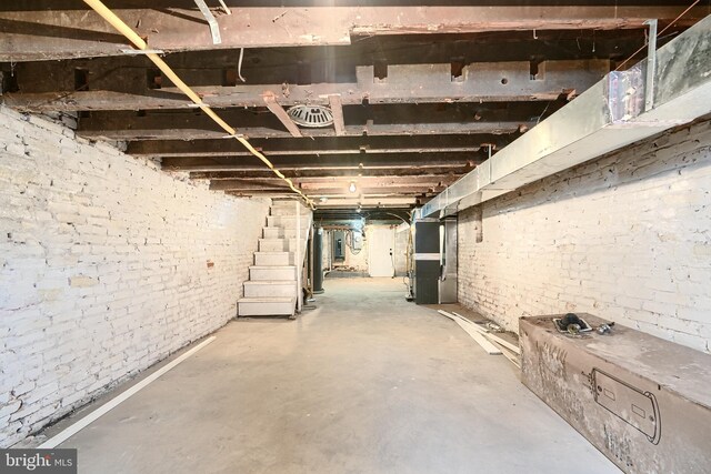 unfinished below grade area with stairs, electric panel, and brick wall