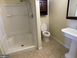 bathroom featuring tile patterned flooring, baseboards, toilet, and walk in shower