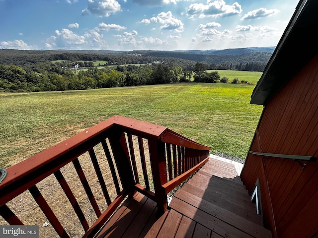 deck featuring a mountain view, a view of trees, a lawn, and a rural view