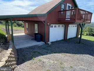 view of home's exterior featuring gravel driveway, a carport, and a detached garage