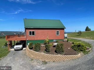 view of side of property with a carport, metal roof, gravel driveway, and a standing seam roof