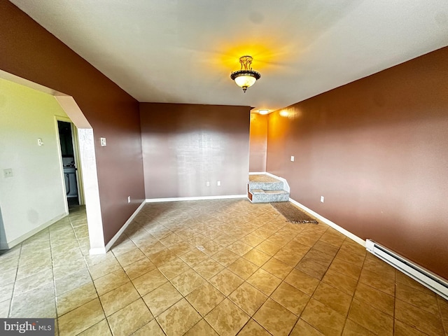 spare room featuring light tile patterned floors, baseboard heating, and baseboards