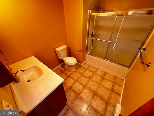 bathroom featuring vanity, baseboards, tile patterned floors, toilet, and combined bath / shower with glass door