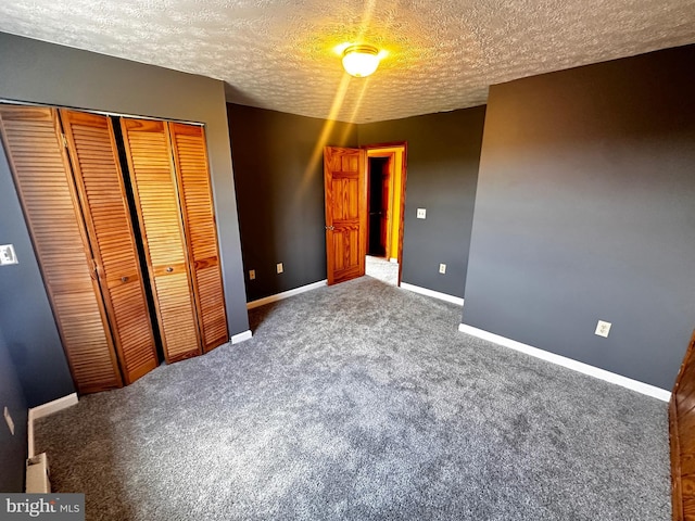 unfurnished bedroom with a closet, baseboards, a textured ceiling, and carpet floors