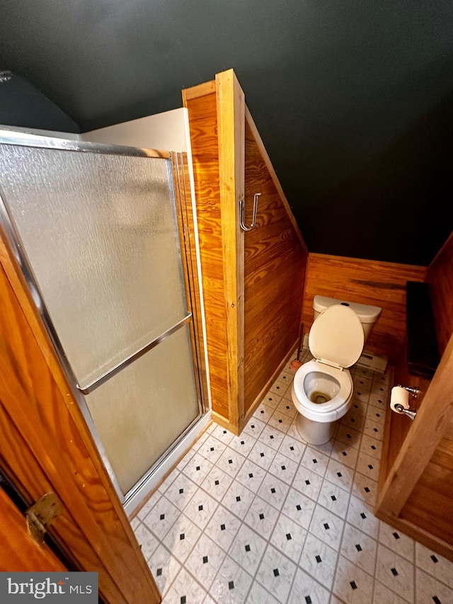 bathroom featuring wooden walls, a shower stall, toilet, and lofted ceiling