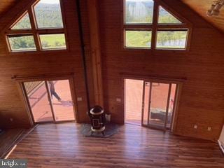 unfurnished living room featuring wood walls, high vaulted ceiling, and wood finished floors