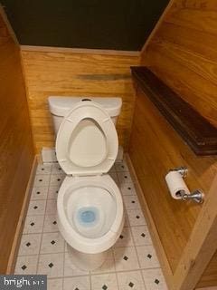 bathroom with toilet, wooden walls, and tile patterned flooring