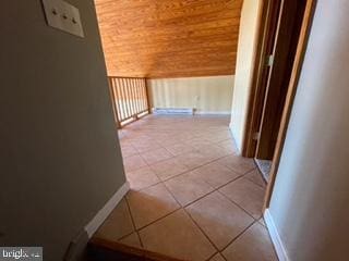 corridor featuring vaulted ceiling, light tile patterned floors, and wooden ceiling