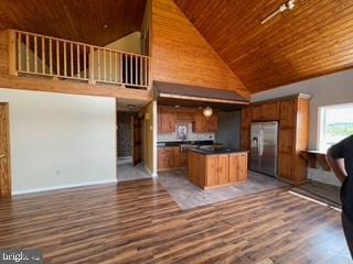 kitchen featuring stainless steel refrigerator with ice dispenser, dark countertops, wood finished floors, open floor plan, and wood ceiling