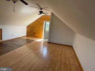 bonus room with baseboards, lofted ceiling, wood finished floors, and a ceiling fan