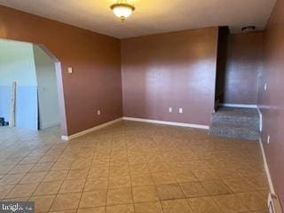 empty room with baseboards and arched walkways