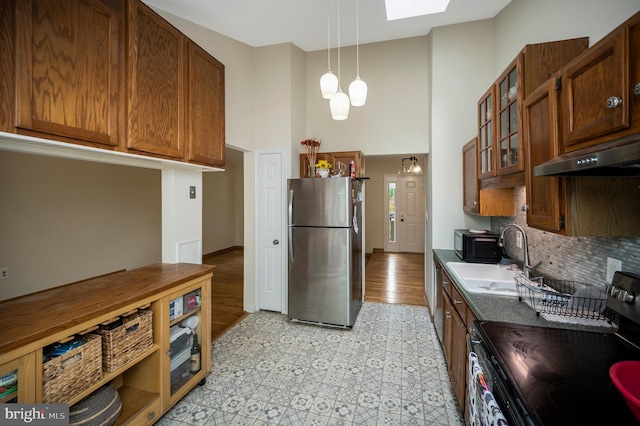 2036 Coast Guard Dr, Stafford, VA 22554 - kitchen with freestanding refrigerator, electric stove, under cabinet range hood, a sink, and a towering ceiling