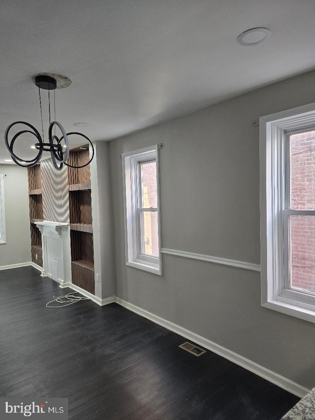 unfurnished dining area with baseboards, visible vents, dark wood-style flooring, and a chandelier