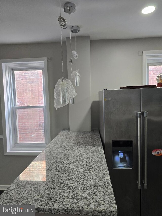 room details featuring stone countertops and stainless steel refrigerator with ice dispenser