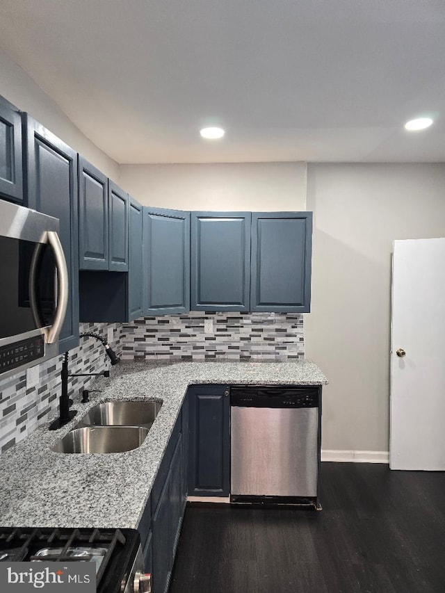 kitchen featuring a sink, light stone counters, backsplash, dark wood finished floors, and stainless steel appliances